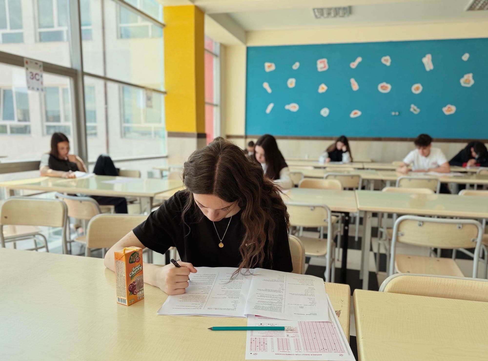 Aydınlık bir sınıfta sınav kâğıdına eğilmiş öğrenci